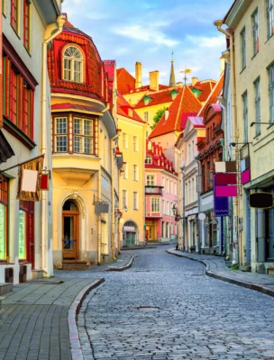 A narrow, colorful cobblestone street lined with historic buildings, featuring pastel facades and ornate architecture.