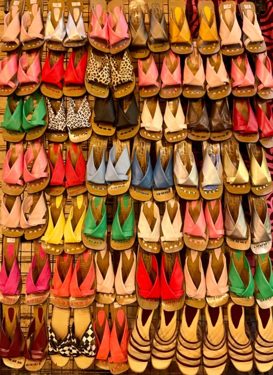 A colorful display of sandals in various styles and colors, neatly arranged in rows on a wall.