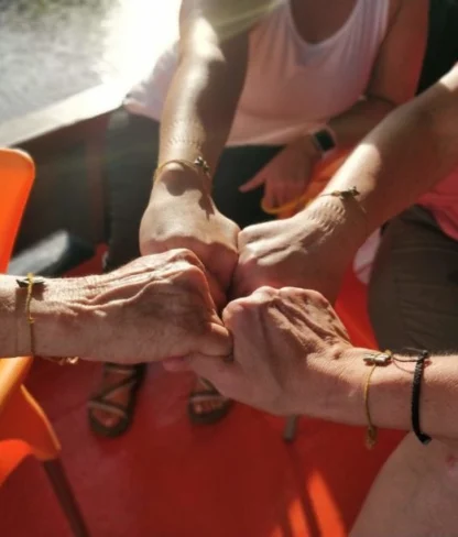 Five people sitting spread their fists in the center, wearing matching bracelets.