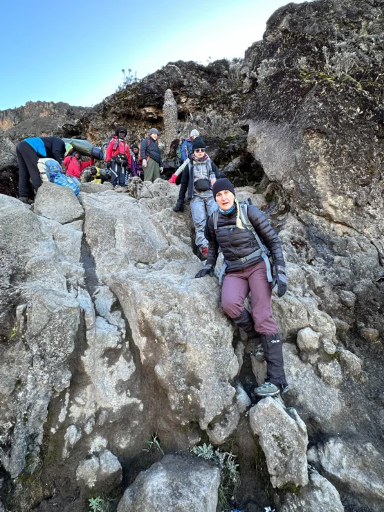 A group of hikers climbing rocky terrain on a mountainous trail.
